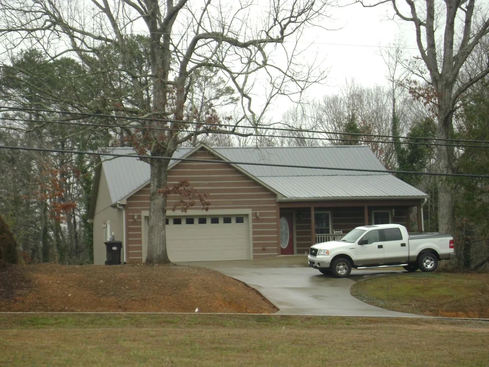 Gray metal roof on a log sided house with an attached two car garage in Enfield