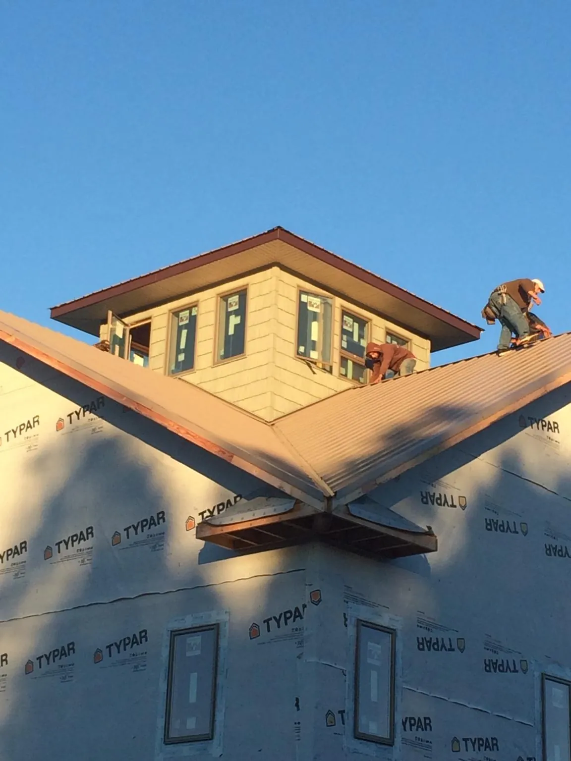 Roofers working around a rooftop cupola on a new metal roof at sunset — Roof Waterproofing in Enfield by Roofing Brothers